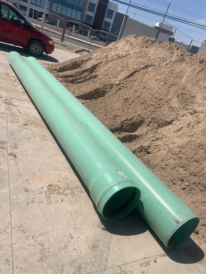 Dos tramos de tubería sanitaria de PVC en el sitio, junto al montón de material excavado