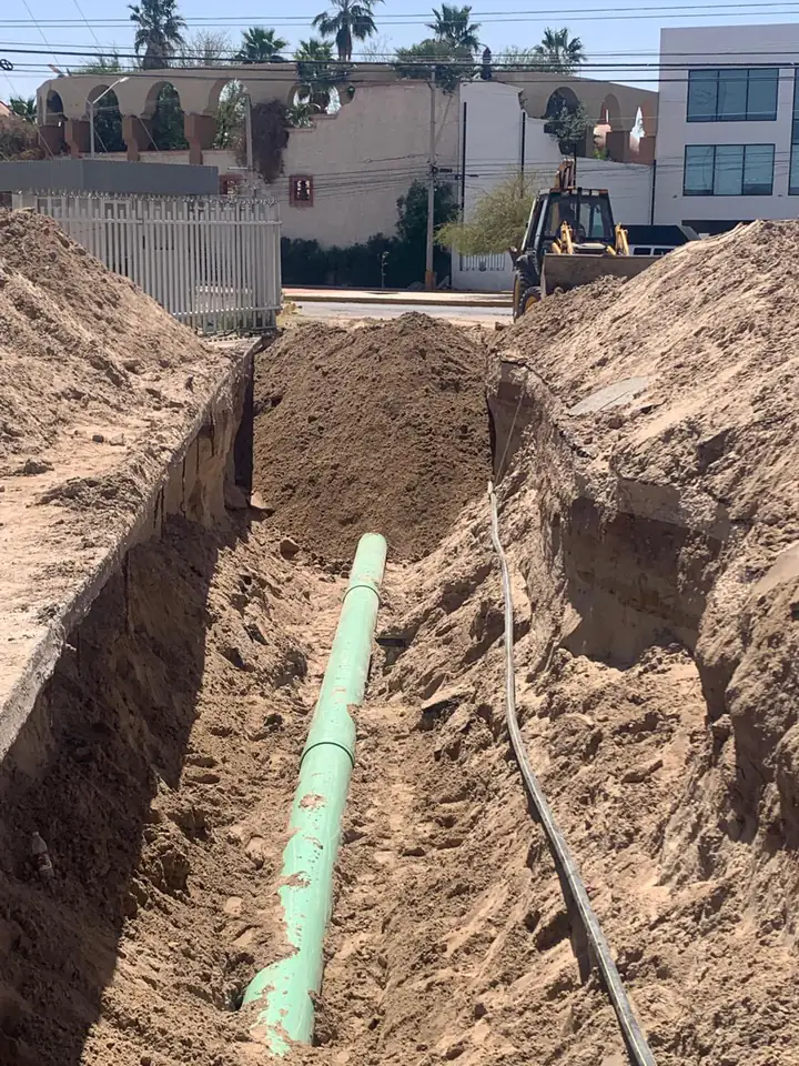 La línea tendida vista desde la calle, con la retroexcavadora iniciando el relleno de la zanja